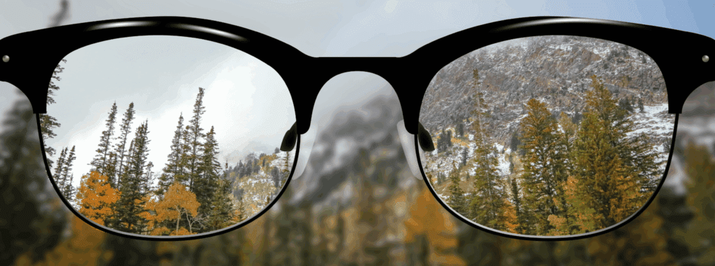 View of clear snowy mountain forest through glasses against the blurred backdrop